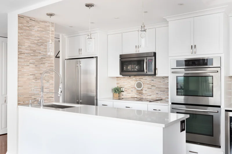 White modern kitchen with stainless steel double oven and refrigerator. White modern kitchen with stainless steel double oven and refrigerator.