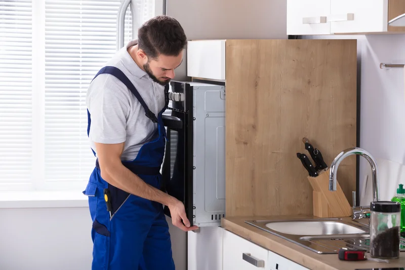 Appliance repair technician installing built-in wall oven Appliance repair technician installing built-in wall oven