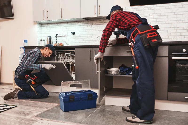 Technicians repairing a built in dishwasher in a modern kitchen Technicians repairing a built in dishwasher in a modern kitchen