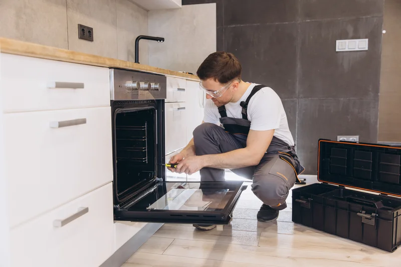 Professional technician repairing a built-in kitchen oven.