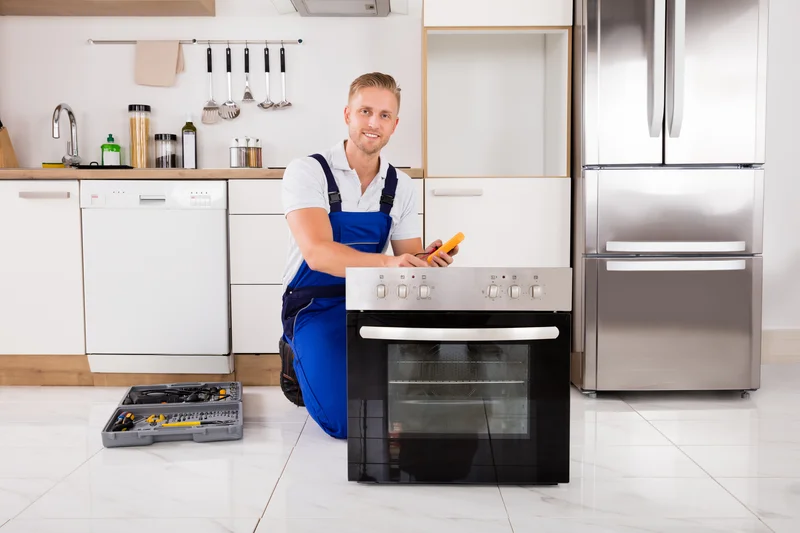 Appliance technician repairing a kitchen oven stove with tools and a multimeter Appliance technician repairing a kitchen oven stove with tools and a multimeter